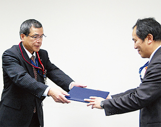 区長に贈呈する桜井局長（左）