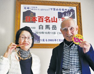 踏破記念に孫が作った金メダルを持つ敏夫さんと直子さん