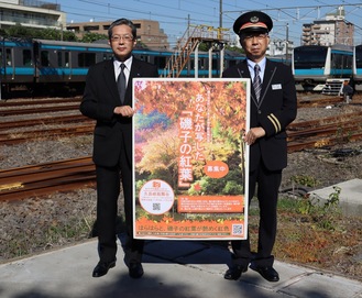 PRポスターを手にする猪俣宏幸磯子区長（左）と林哲治磯子駅長