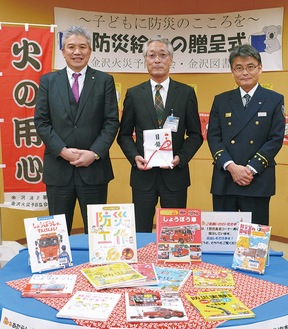 寄贈した本と児玉会長、上條館長、金沢消防署の和知治署長（左から）