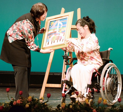 塚田さん（右）から絵画を受け取る中村館長