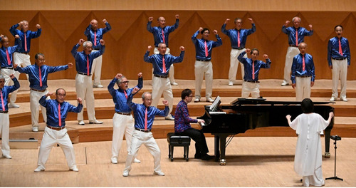 振り付けを交え歌う団員たち＝同団体提供