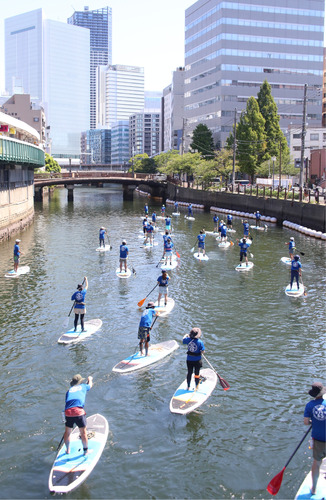 横浜市庁舎（左奥）へ向かって大岡川をＳＵＰで進む参加者