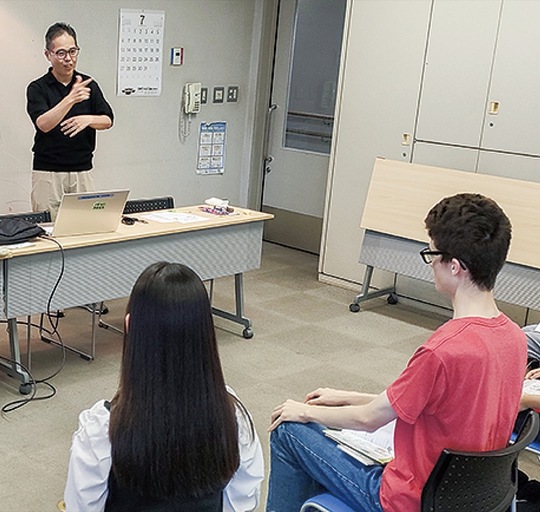 手話講座であいさつする市聴覚障害者協会の小島理事長（左奥）