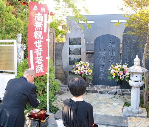 慰霊碑を前に手を合わせる参拝者＝7月25日