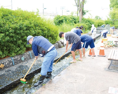 デッキブラシで清掃する参加者たち