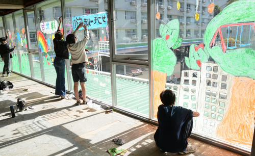 ガラスに団地などの絵を描く児童たち