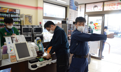 ２人組の犯人役とレジで対応するスタッフ（左）