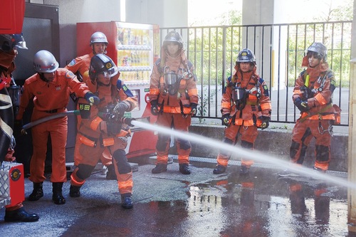 防火服を着てホースでの放水を体験する生徒