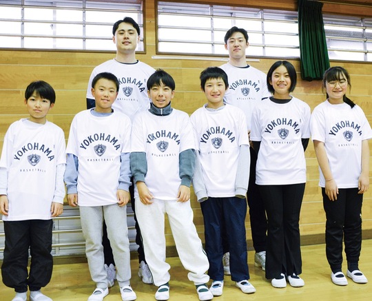 寄贈されたＴシャツ着た松崎選手（後列左）と前野選手（同右）、代表の児童たち