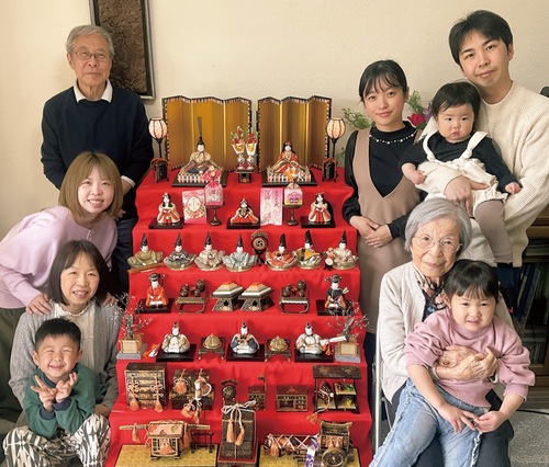 七段飾りを囲む松本さん家族。右側前から２人目が道子さん、左側前から２人目が極美さん、３人目が彩加さん