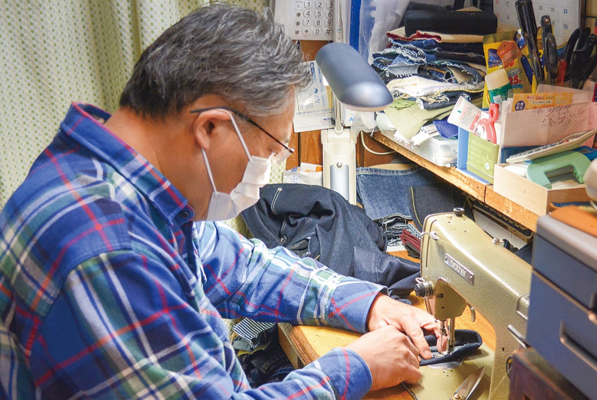 ミシンで裾上げをする高岡社長