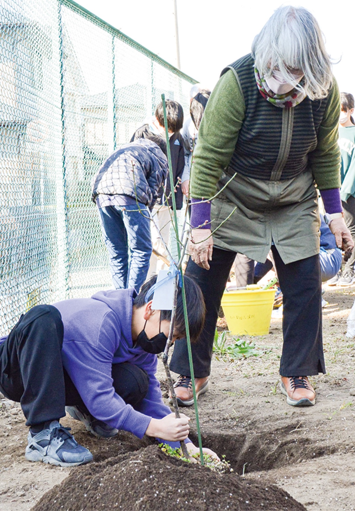 秋葉さん(右)と苗木を植える児童