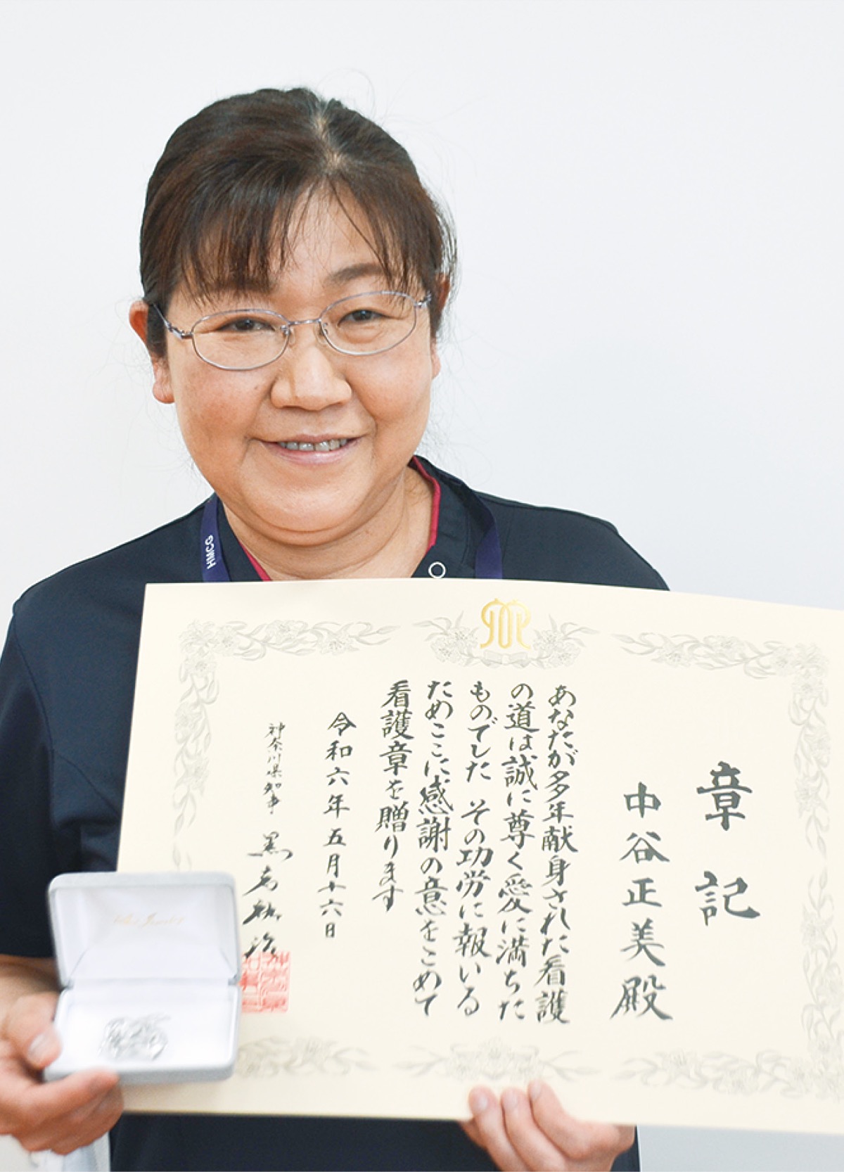 贈られた賞状とブローチを持つ中谷さん