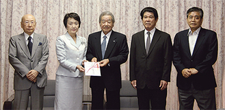 林市長（左から２人目）に目録を手渡す鈴木代表取締役（中央）