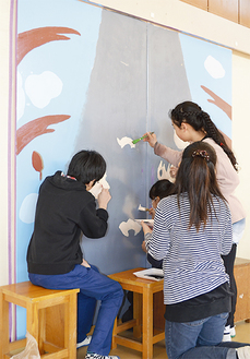 体育館の扉に絵を描く児童たち