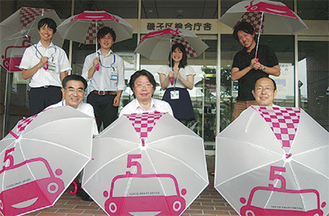 傘を手にする山本代表（前列中央）と区職員