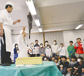 松崎さん（左から２番目）からアンコウについての説明を聞く子どもたち