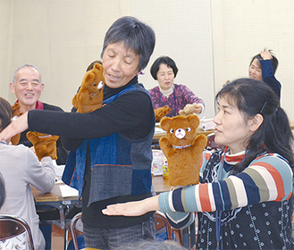 講師から人形の動かし方を学ぶ参加者（右）