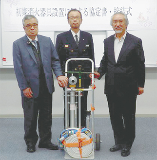 協定の締結式で器具を手にする小島会長（写真右）と青木署長（中央）、石井オーナー
