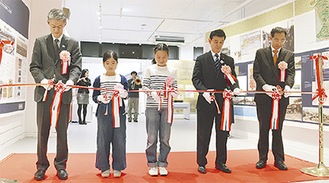テープカットを行う左から加賀局長、石津さん、原さん、小林区長、山崎理事長