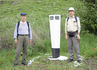カザフスタン東部の農村地帯にて。右が跡部さん。中央の標識は旧共産圏の国には必ず１Km毎に建てられているというマイル・ストーン