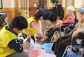 岩手県大槌町で高齢者の足浴を手伝う明学大生