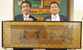 海舟の書を持つ岡田校長（左）と松本理孝副校長