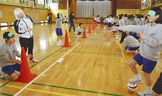 内田さん（左から２人目）のアドバイスを受け、ボールワークに取り組む生徒たち