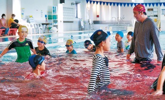 着衣のままプールに入って泳ぎ方やもしもの場合の対処法を学ぶ子どもたち