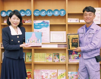 寄贈した本を手にする鈴木館長（左）と木村代表