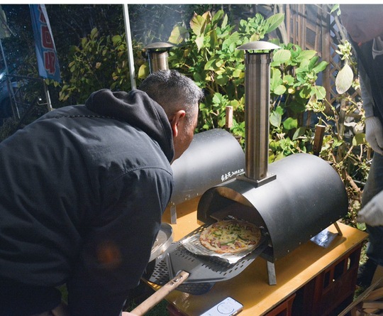 窯からピザを取り出す会員