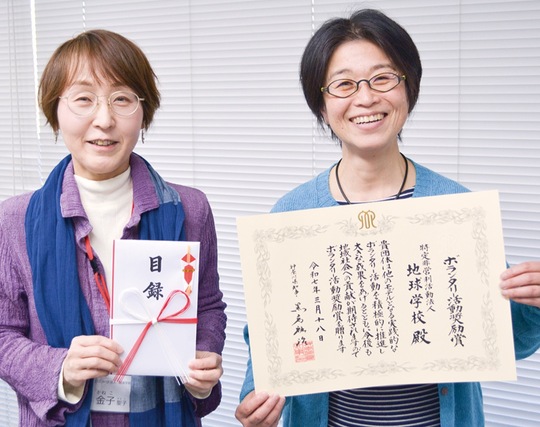 賞状を手にする地球学校の丸山理事長と金子さん
