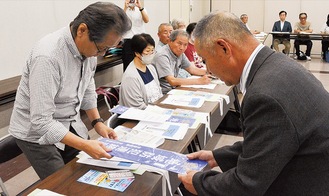 看板を渡す横川会長（右）