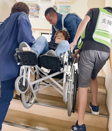 車いすに乗った人を階段で上げるデモンストレーション＝港南中央地域ケアプラザ