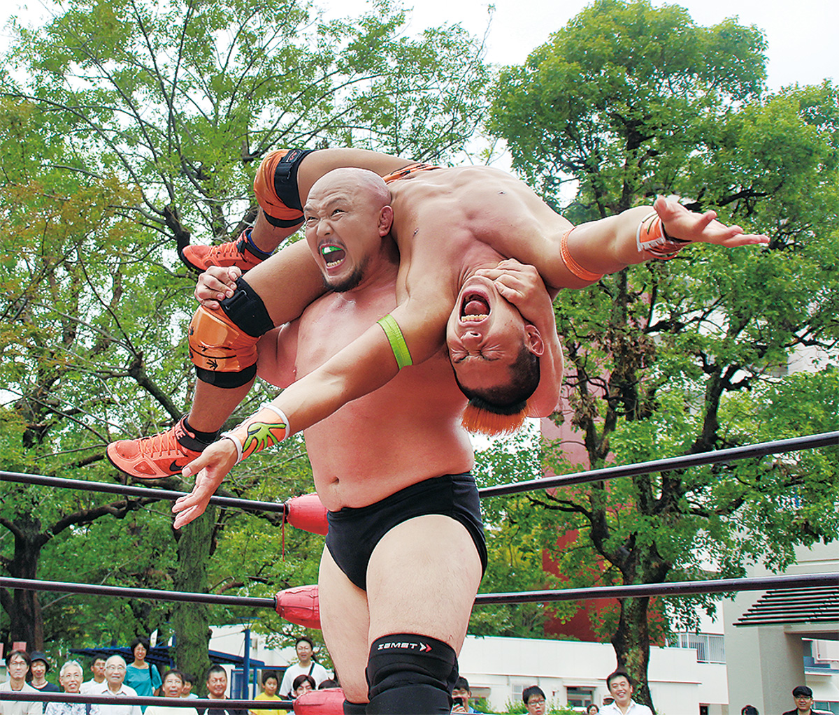観客が見守る中、技を決めるプロレスラー