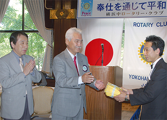 千田会長（中央）からハンカチ３００枚がホテルニューグランドに寄贈された＝5月31日の例会で