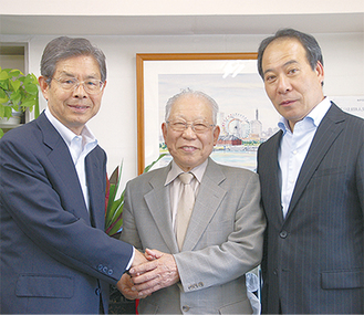 帆船日本丸記念財団の金近会長と握手を交わす石田名誉船長（中央）。右は同財団の佐野総務部長