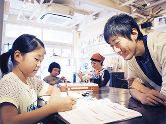 カフェで勉強を教える小林さん（右）。「塾とは違うけれど、寺子屋のような雰囲気で学習の習慣がつくよう支援できれば」