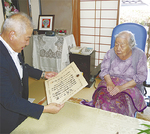 三上区長から祝状を贈られる中村さん（写真右）