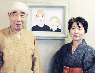 肖像画の前で舞眞顕さん・美代子さん夫妻