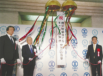 くす玉開きで祝う小谷社長（中央）、岡田店長（左）