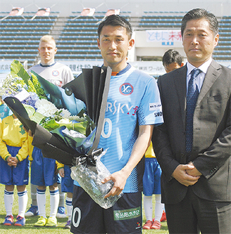 ＹＳＣＣの吉野次郎理事長（右）から記念の花束を受け取る吉田選手
