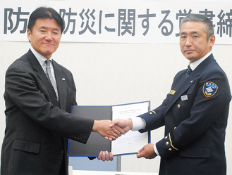 覚書への署名を終え、握手を交わすテレビ神奈川ecom事業局の伊藤局長（左）と西消防署の宮川署長