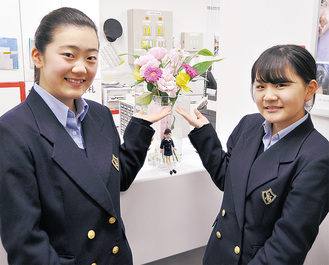 JR石川町駅南口のみどりの窓口に飾られた花の前で、委員長の高山さん（左）と副委員長の牧嶋さん。花の状態を見ながら週１回ほどのペースで生け替えている