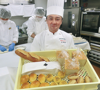 「ニューグランドらしさを追求した」と焼立てのパンを手に、製パン担当の原田さん＝ホテルベーカリー工房にて