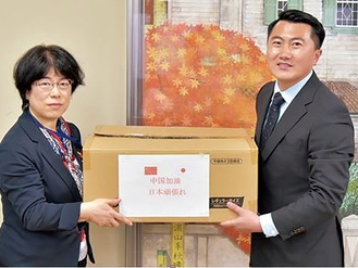 マスクを寄付する内蒙古中日友好言語センターの李副会長（右）