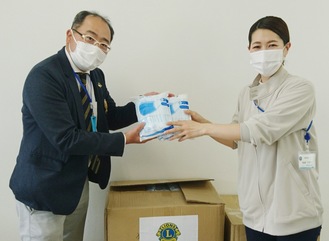横浜ライオンズクラブの鈴木会長（左）とマスクを受け取るケアホーム横浜の事務長・衛藤久美子さん
