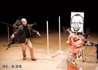 田井実行委員長（左）の似顔絵を歌いながら描いた桜小路富士丸さん