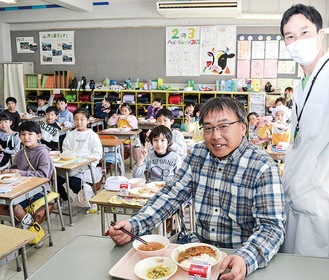 児童と給食を共にする山岡さん（中央）と大庭教諭